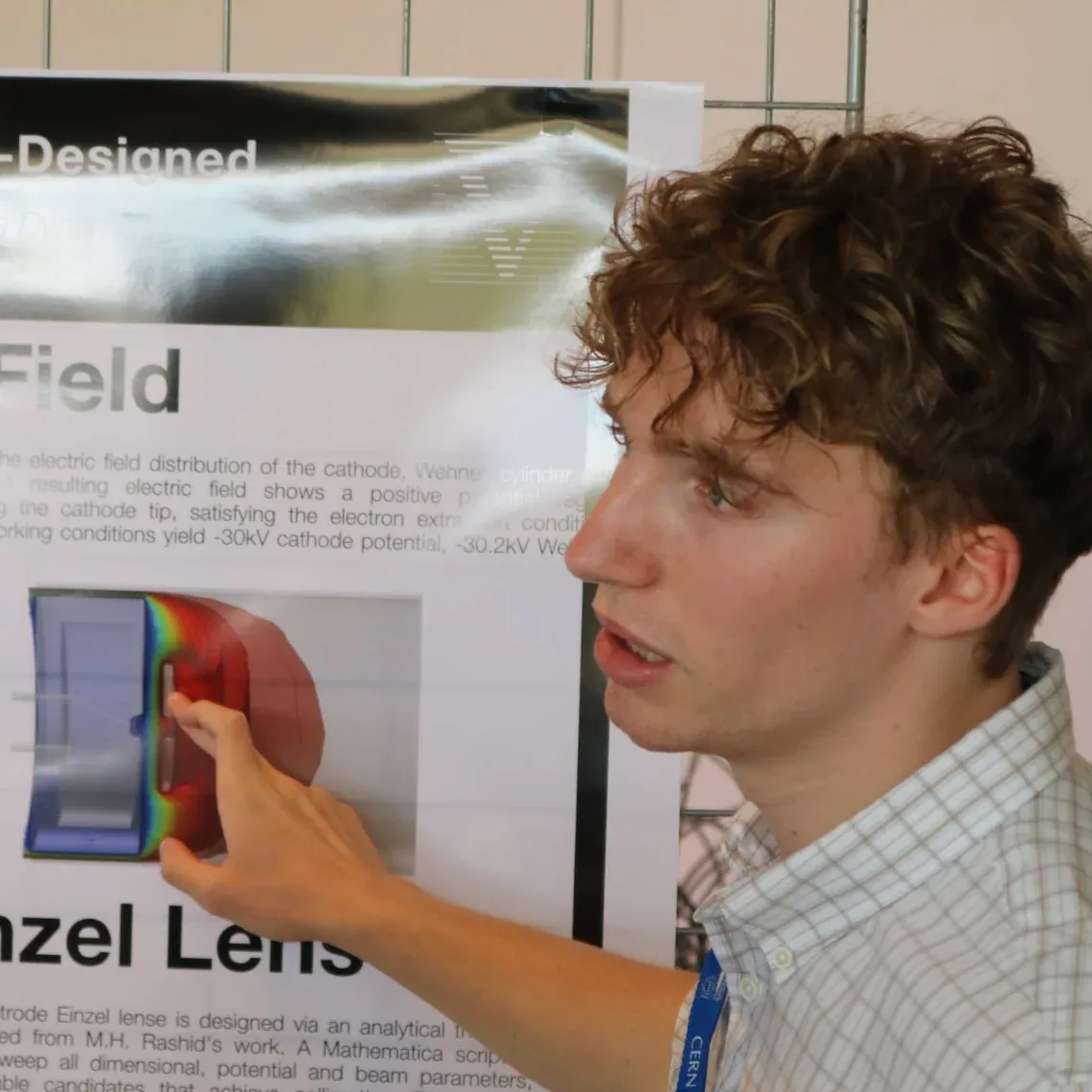 Arlen Boesch presents our poster at CERN, pointing at a field simulation.