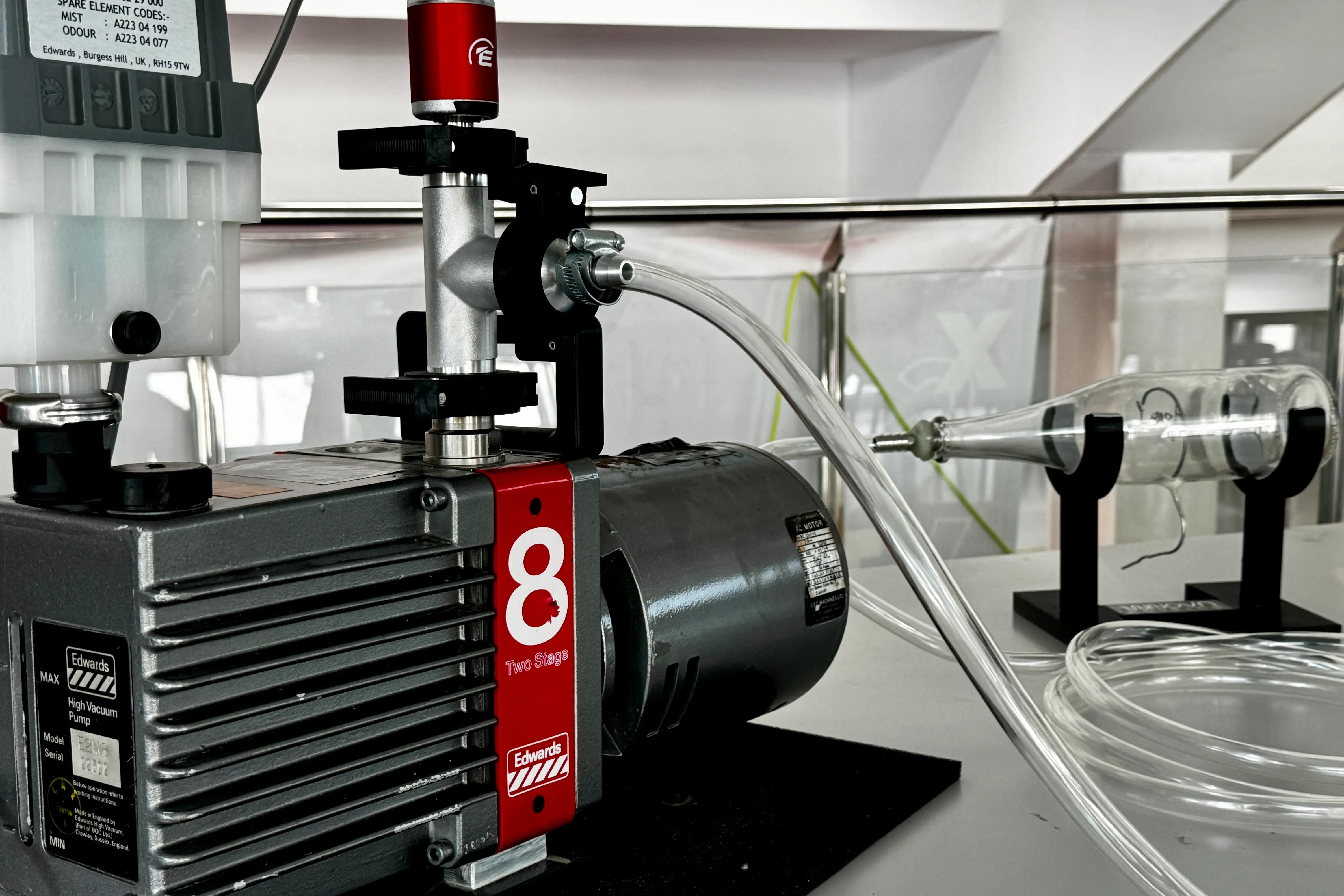 Model-0 on the bench: an Edwards vacuum pump connected to the glass tube where the discharge glows.